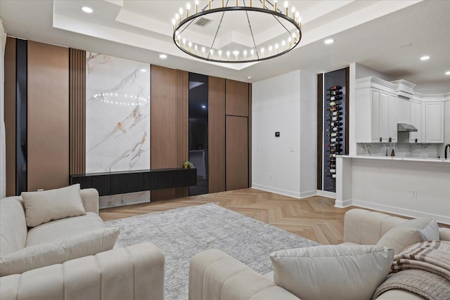 living room with a notable chandelier, light parquet floors, and a tray ceiling