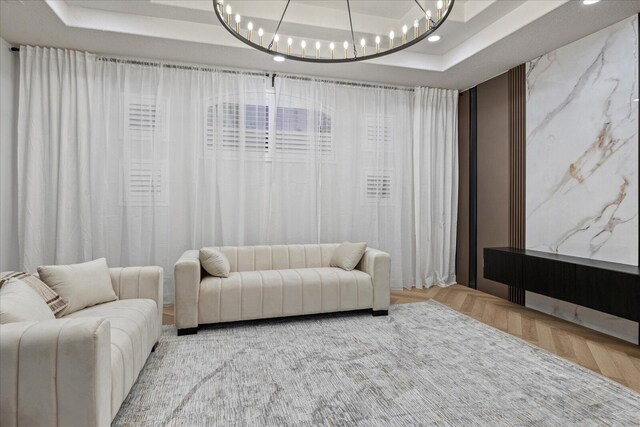 cinema room featuring parquet flooring, an inviting chandelier, and a raised ceiling