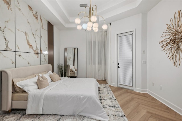 bedroom with a raised ceiling, light parquet flooring, and a notable chandelier