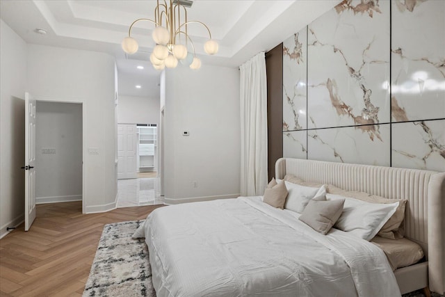 bedroom featuring a tray ceiling, light parquet floors, and a notable chandelier