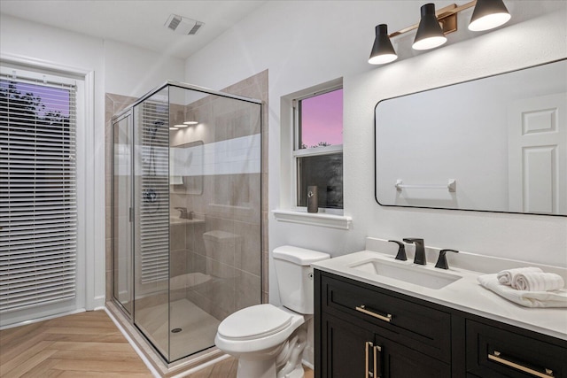 bathroom featuring an enclosed shower, vanity, toilet, and parquet flooring