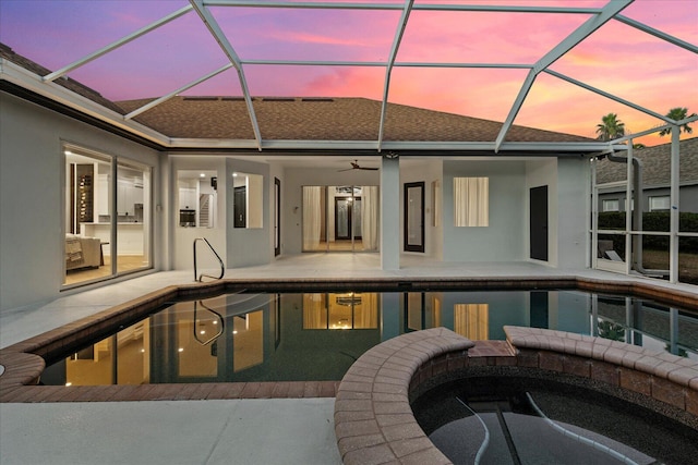 pool at dusk with glass enclosure, an in ground hot tub, a patio area, and ceiling fan