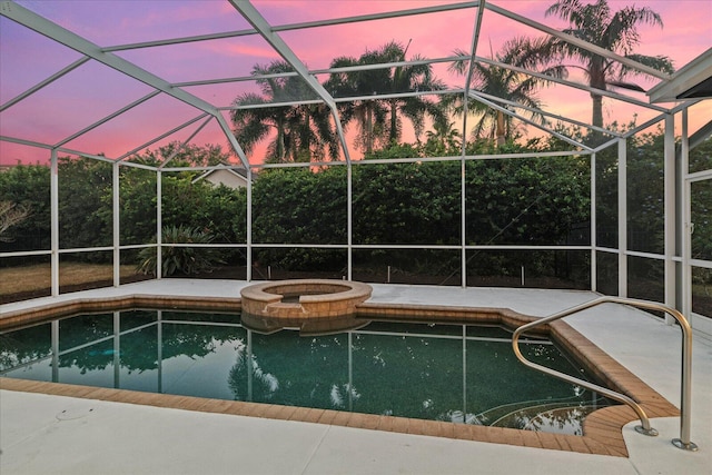 pool at dusk with a lanai and an in ground hot tub