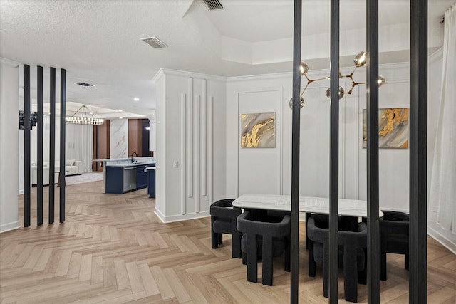 interior space with a textured ceiling, light parquet floors, and sink