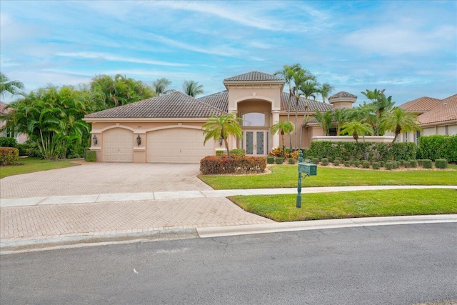 mediterranean / spanish-style home with french doors, a garage, and a front lawn