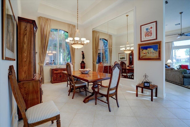 tiled dining space featuring ceiling fan with notable chandelier and a tray ceiling