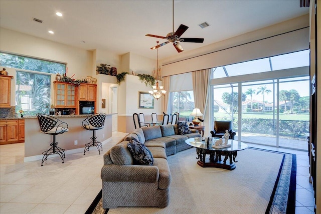 tiled living room with ceiling fan with notable chandelier and a healthy amount of sunlight