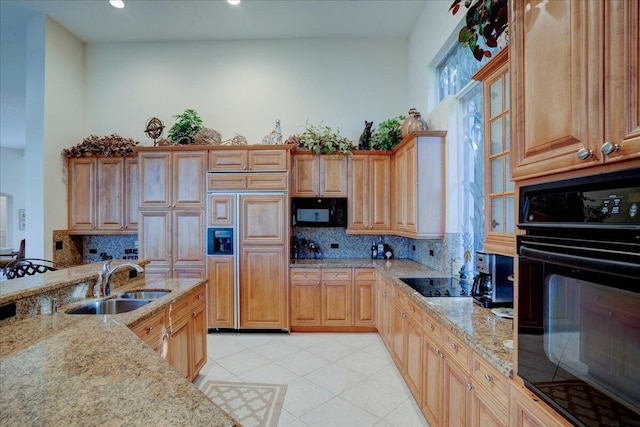 kitchen featuring light stone countertops, sink, tasteful backsplash, and black appliances