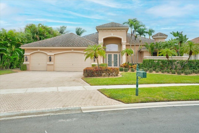 mediterranean / spanish-style house featuring a front yard, french doors, and a garage