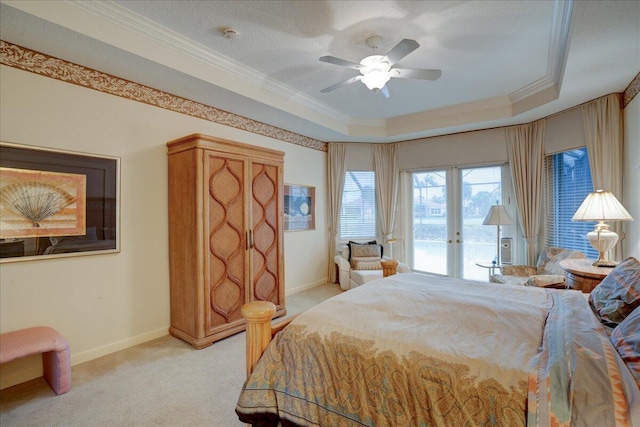 bedroom featuring ceiling fan, light colored carpet, access to outside, a tray ceiling, and ornamental molding