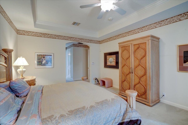 carpeted bedroom with a raised ceiling, ceiling fan, and ornamental molding