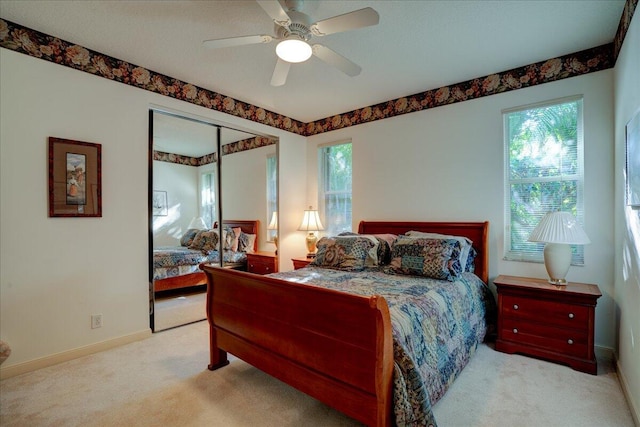 carpeted bedroom with multiple windows, a closet, and ceiling fan