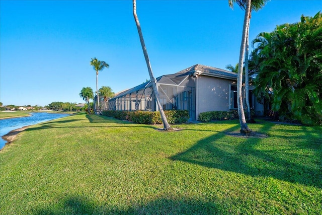 view of yard with a lanai and a water view