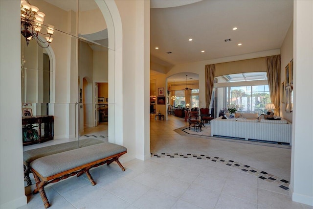 hallway with light tile patterned flooring and a notable chandelier