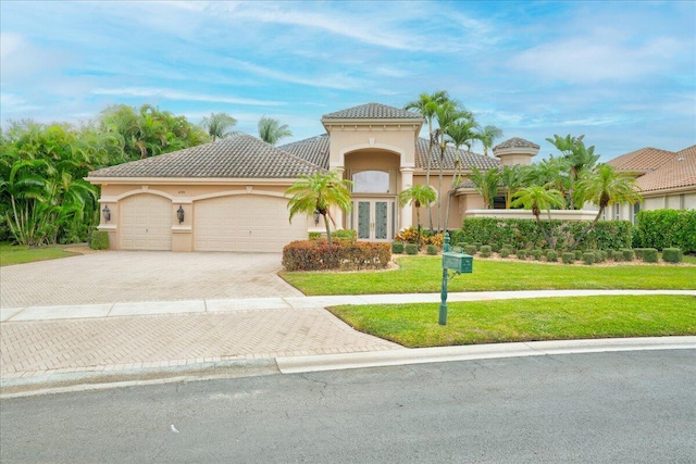 mediterranean / spanish home featuring french doors, a front lawn, and a garage