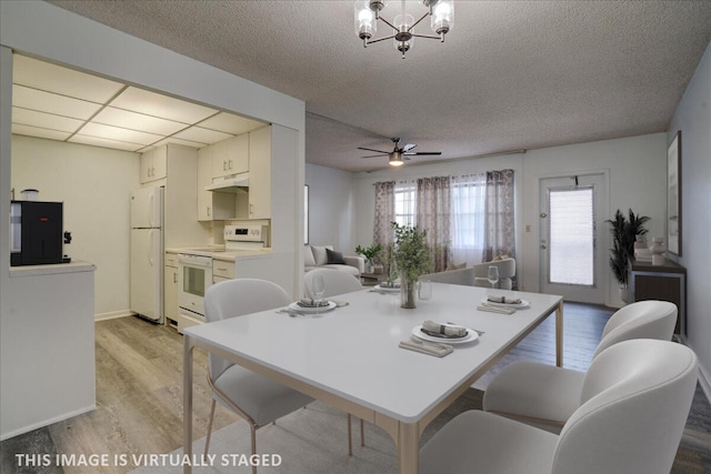 dining space with a textured ceiling, light hardwood / wood-style flooring, and ceiling fan with notable chandelier