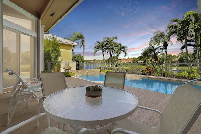 pool at dusk featuring a patio