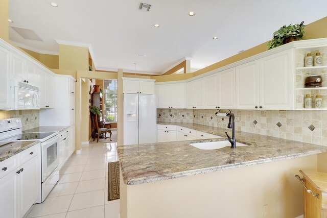 kitchen featuring sink, white cabinets, kitchen peninsula, light stone countertops, and white appliances