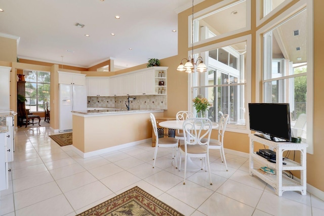 tiled dining space featuring crown molding, a chandelier, and a healthy amount of sunlight