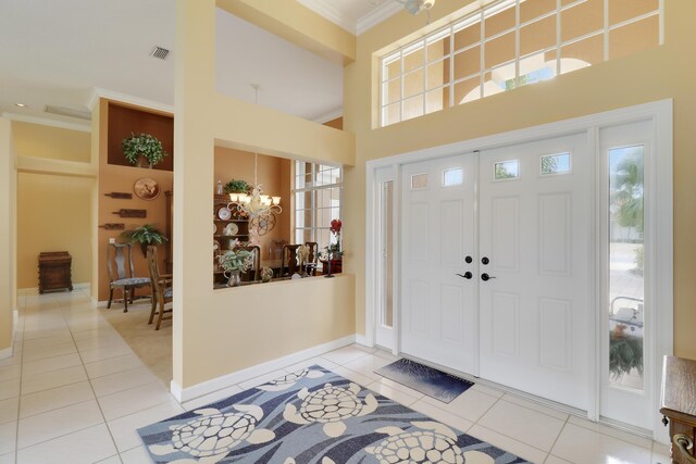 entrance foyer featuring tile patterned flooring, crown molding, and a chandelier