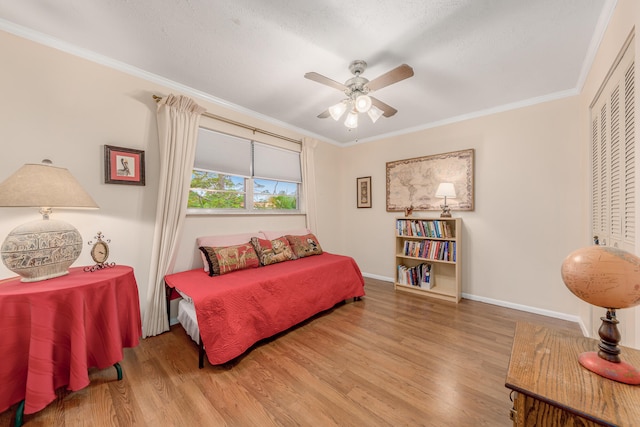 bedroom with ceiling fan, light wood-type flooring, crown molding, and a closet