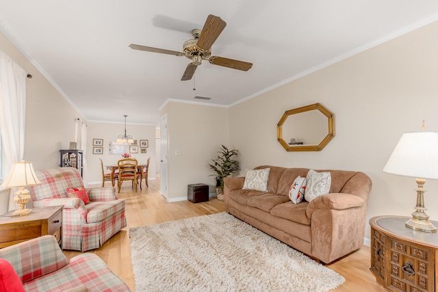 living room with ceiling fan with notable chandelier, light hardwood / wood-style flooring, and crown molding