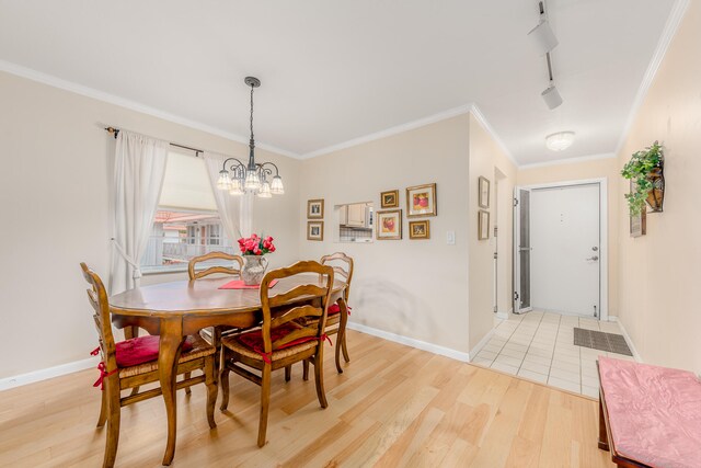 dining room featuring light hardwood / wood-style floors, crown molding, rail lighting, and an inviting chandelier