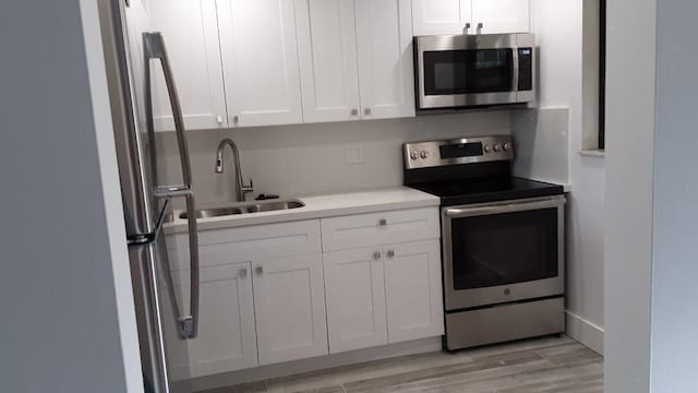 kitchen featuring light hardwood / wood-style flooring, stainless steel appliances, white cabinetry, and sink