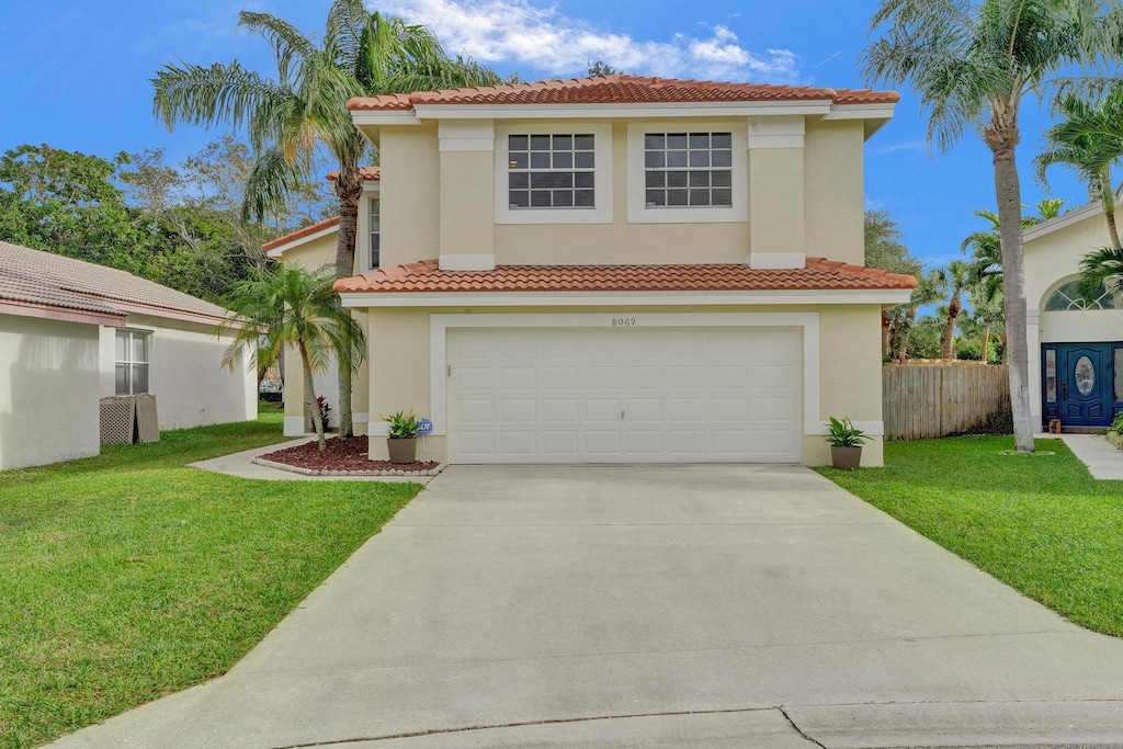 mediterranean / spanish-style house with a garage and a front lawn