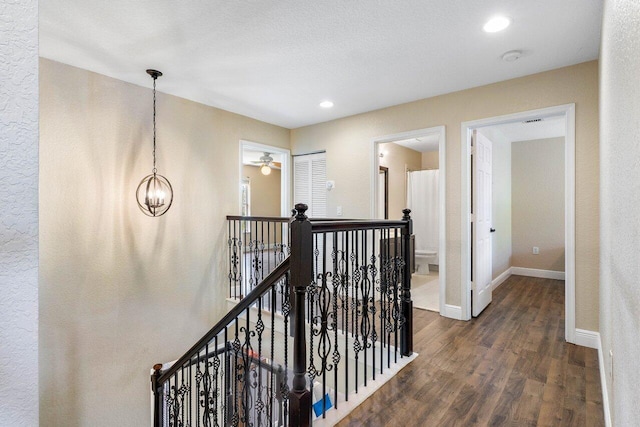 corridor featuring a textured ceiling, a notable chandelier, and dark wood-type flooring