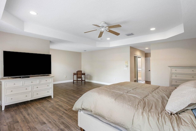 bedroom featuring a textured ceiling, ceiling fan, dark wood-type flooring, and a tray ceiling