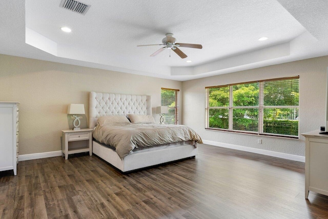 bedroom featuring a textured ceiling, a raised ceiling, ceiling fan, and dark wood-type flooring