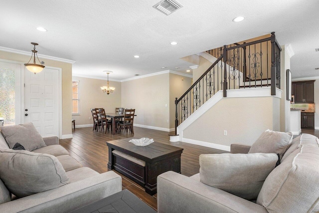 living room featuring a textured ceiling, dark hardwood / wood-style flooring, crown molding, and a chandelier