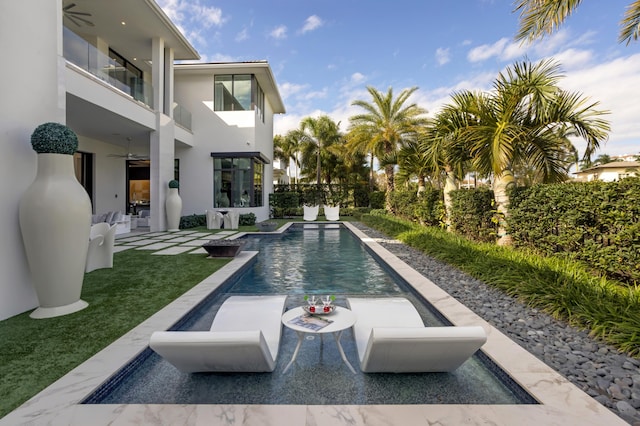 view of pool with ceiling fan and a yard