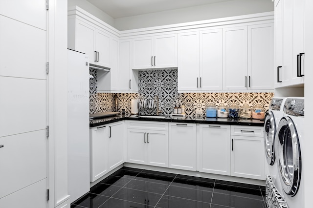 kitchen featuring decorative backsplash, dark tile patterned floors, sink, separate washer and dryer, and white cabinets