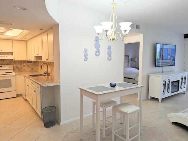 kitchen featuring pendant lighting, sink, electric range, light stone countertops, and a notable chandelier