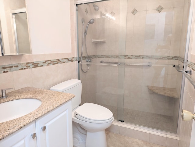 bathroom with vanity, a shower with door, toilet, and tile walls