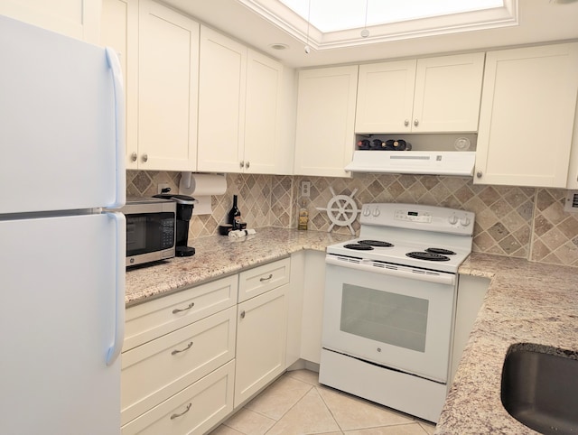 kitchen with light stone countertops, tasteful backsplash, white appliances, range hood, and light tile patterned flooring