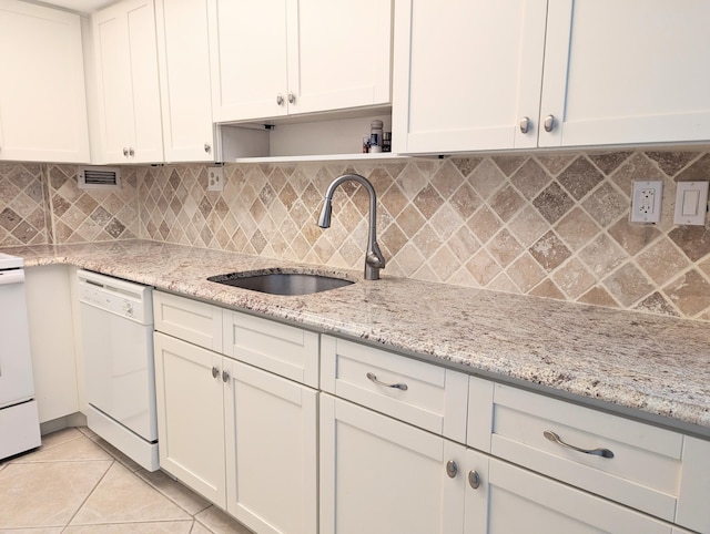 kitchen with light stone countertops, sink, white dishwasher, and light tile patterned floors