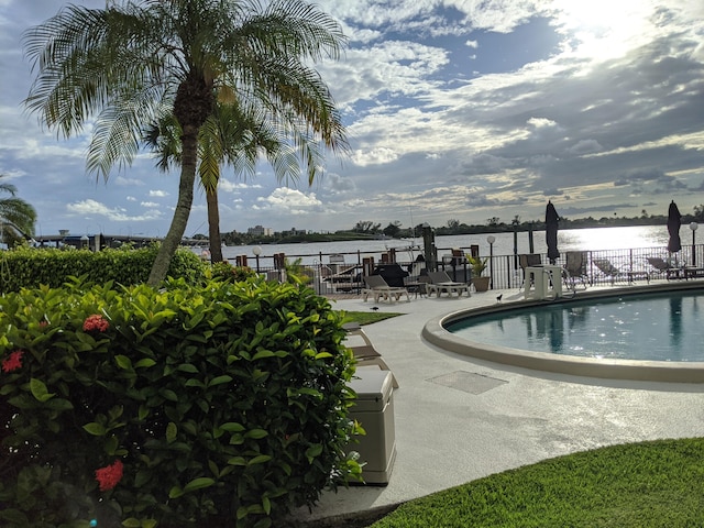 view of swimming pool featuring a water view and a patio area