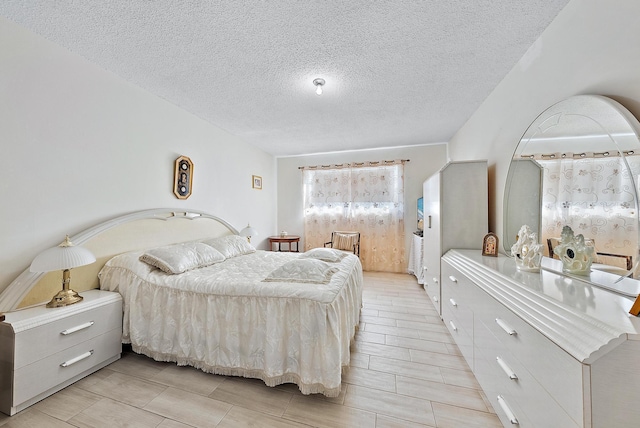 bedroom with a textured ceiling and light hardwood / wood-style flooring