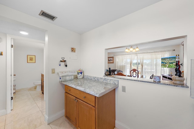 kitchen featuring kitchen peninsula, light stone counters, and light tile patterned floors