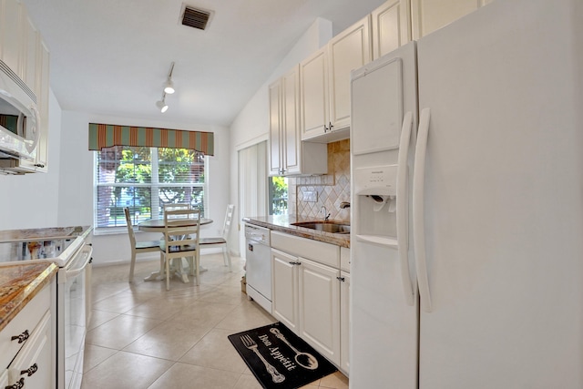 kitchen featuring lofted ceiling, white appliances, white cabinets, sink, and light tile patterned floors