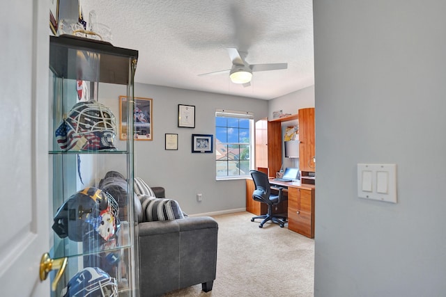 carpeted home office with a textured ceiling and ceiling fan