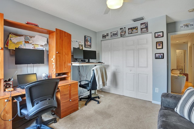 carpeted home office with a textured ceiling and ceiling fan