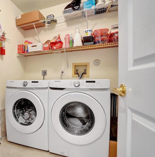 laundry room featuring light tile patterned floors, a textured ceiling, and washer and clothes dryer