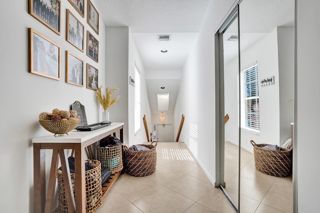 corridor featuring light tile patterned floors and a textured ceiling