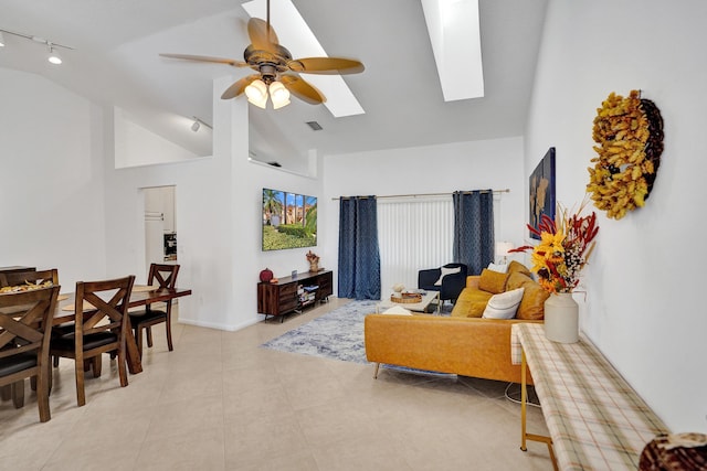 living room with ceiling fan, a skylight, high vaulted ceiling, track lighting, and light tile patterned flooring