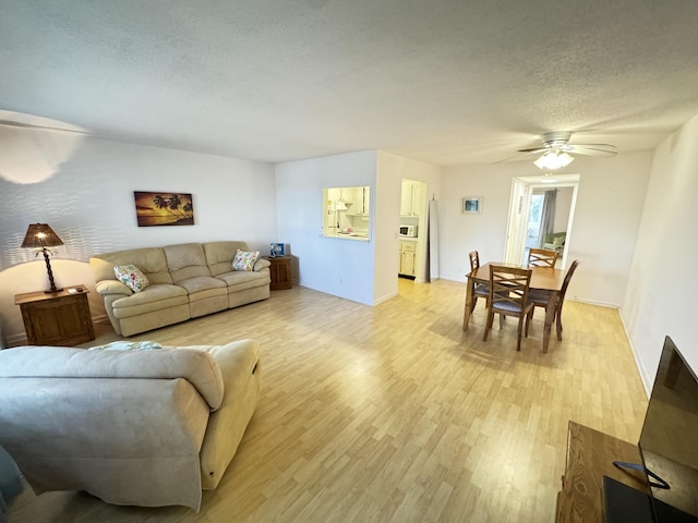 living room featuring a textured ceiling, light wood-type flooring, and ceiling fan