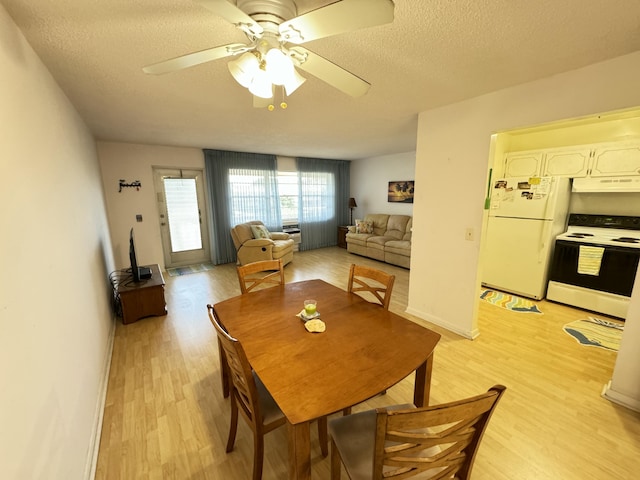 dining room with ceiling fan, a textured ceiling, and light wood-type flooring